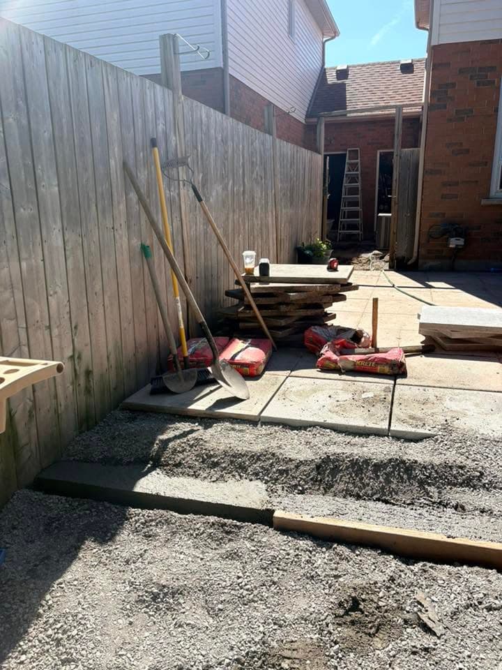 Backyard before the patio build, with gravel base and materials ready