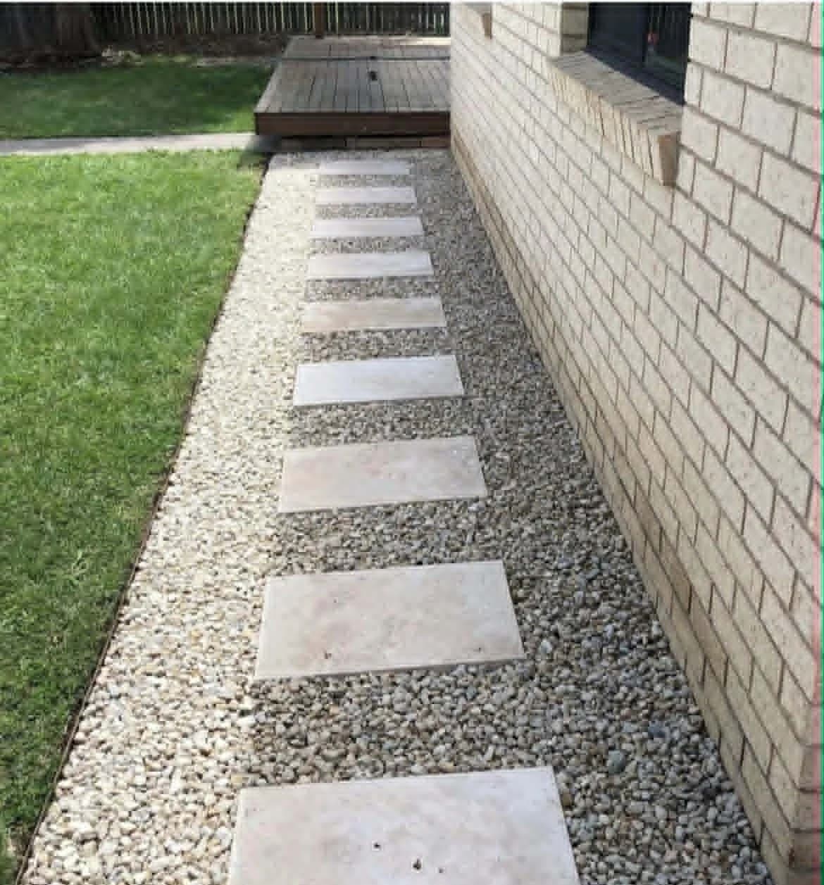 Natural stone stepping-stone walkway set in clean gravel beside a home
